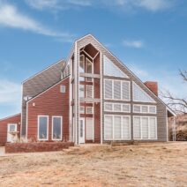 A home in Texas is protected by Klauer’s steel siding in Sunset Red and Terra Bronze. The yard is a desert-like terrain and blue skies are behind it.