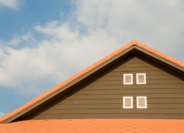 The roof of a home with metal siding in front of blue skies dotted with clouds